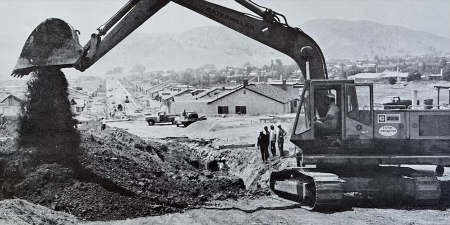 Vintage photo of Caterpillar 225 excavator dumping dirt out of bucket on job site.