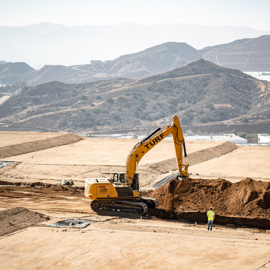 Turf Construction Caterpillar 336 excavator digging trench on job site for underground utilities.
